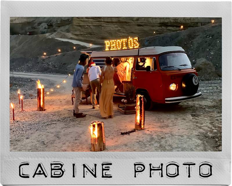 Voiture de collection Photobus loué dans sable éclairé en nuit par torches (image instantanée)