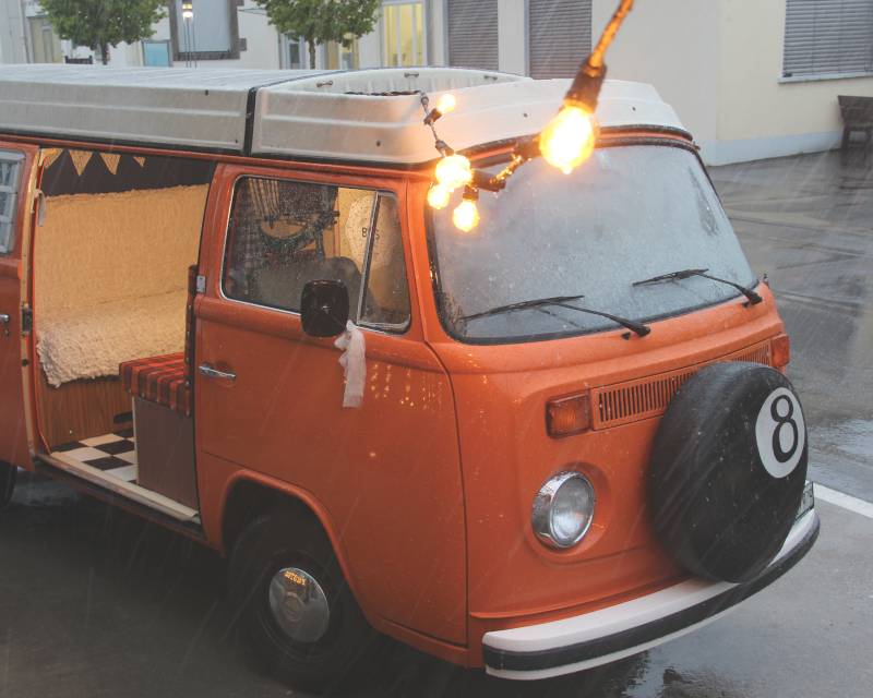Lichterkette an orangem VW-Bus mit Fotobox