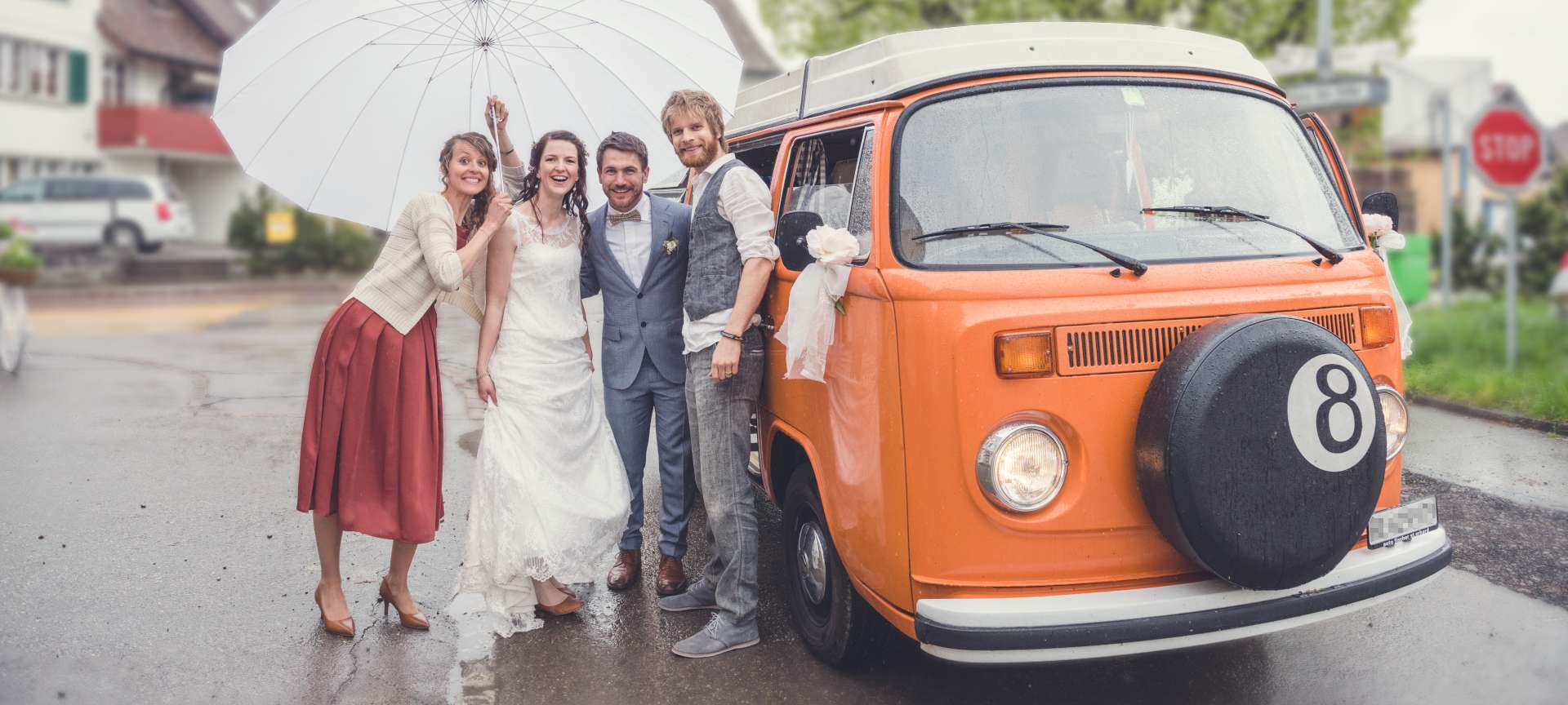 Mariés sous grand parapluie blanc avec le chauffeur de la location de bus VW