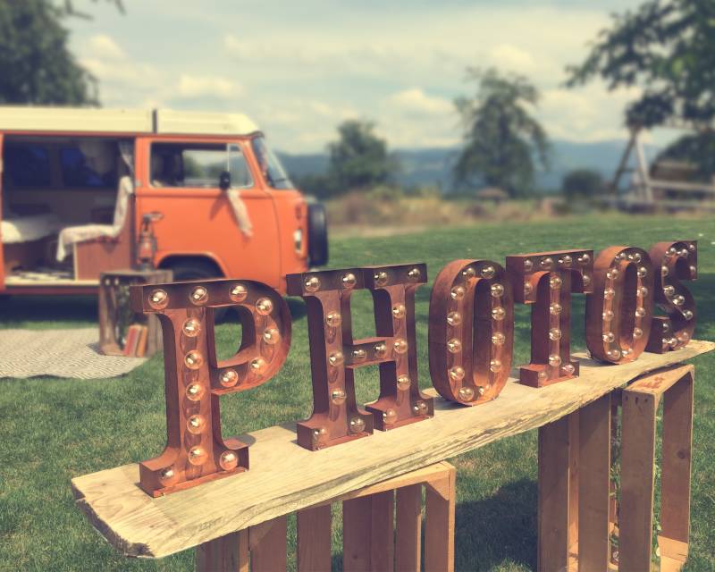Vintage Leuchtbuchstaben vor orangem Fotobus im Hintergrund
