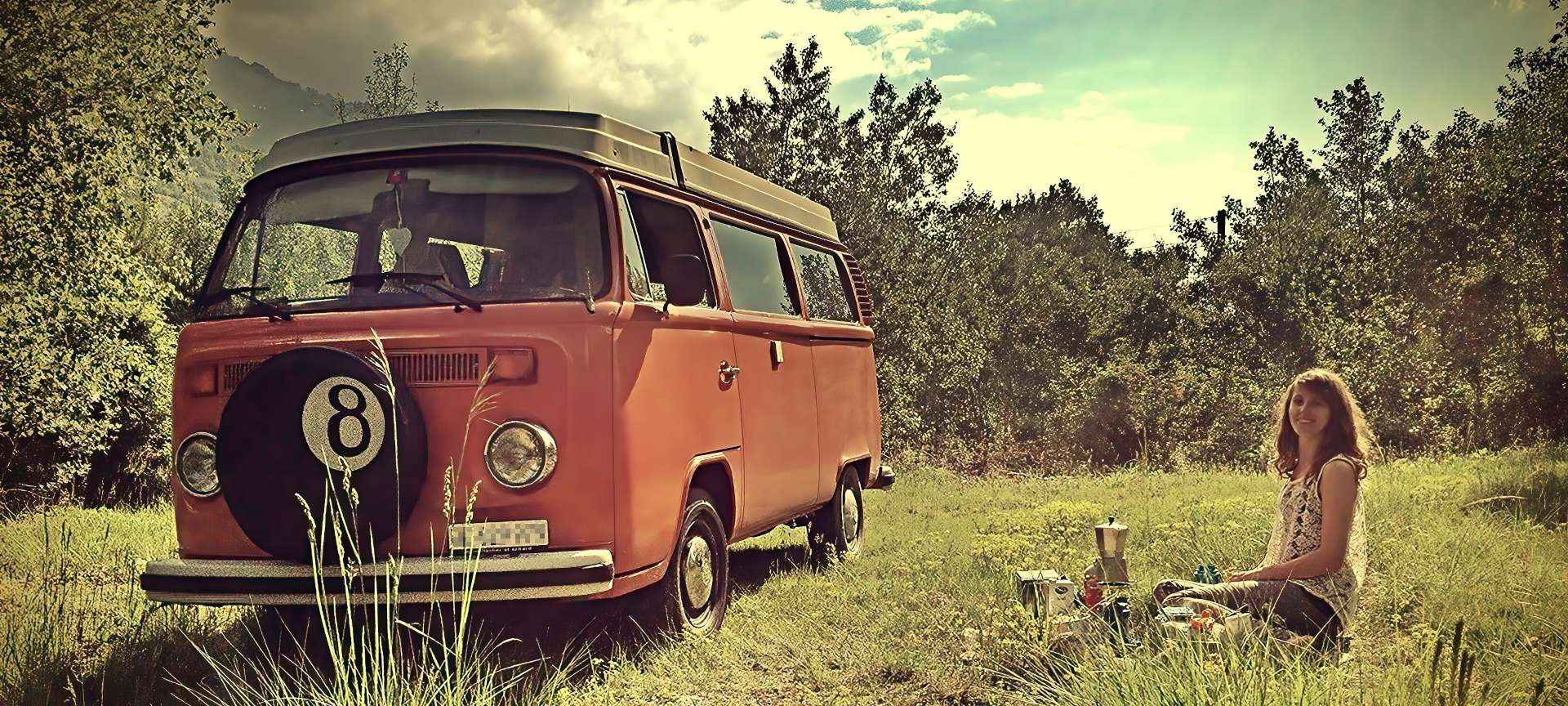 schöne Frau bei nostalgischem Picknick in Natur mit gemietetem altem VW-Bus